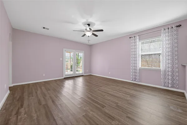 a view of an empty room with a window and wooden floor