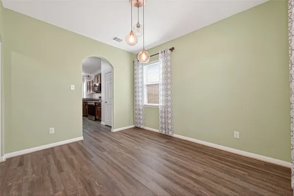 a view of an empty room with window and wooden floor