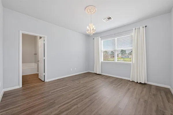an empty room with wooden floor chandelier and windows
