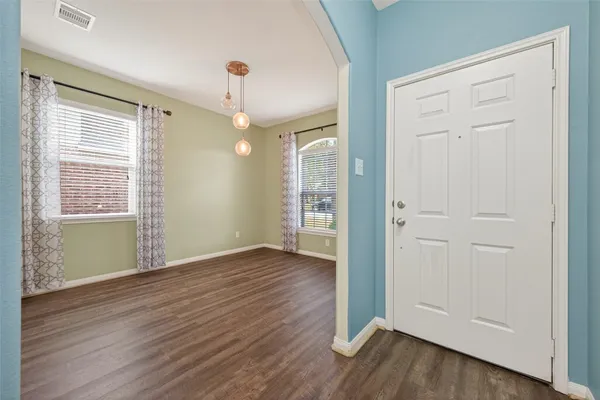 an empty room with wooden floor cabinet and windows