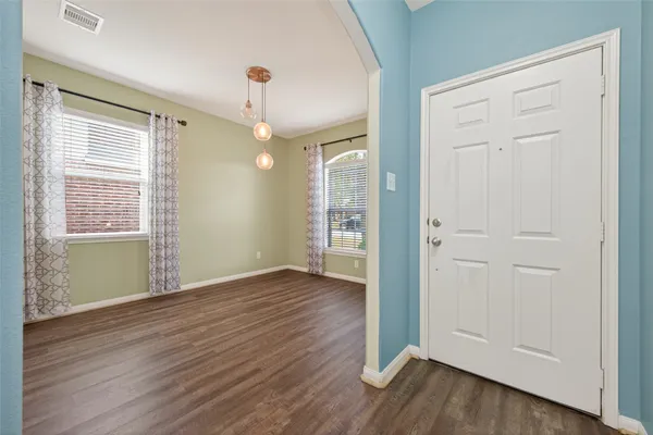 an empty room with wooden floor cabinet and windows