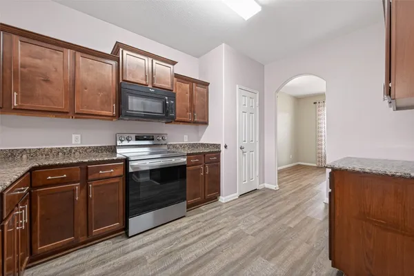 a kitchen with stainless steel appliances granite countertop a stove top oven a sink dishwasher and microwave oven with cabinets