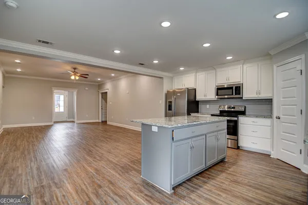 a kitchen with stainless steel appliances granite countertop a stove top oven a sink dishwasher a refrigerator and cabinets with wooden floor