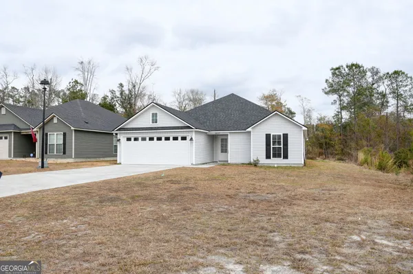 a view of house with yard and trees in the background