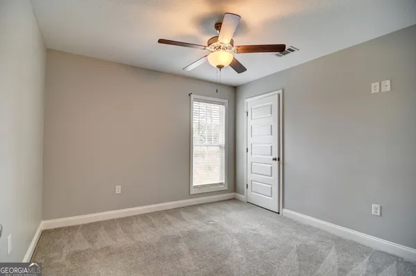 an empty room with windows and fan