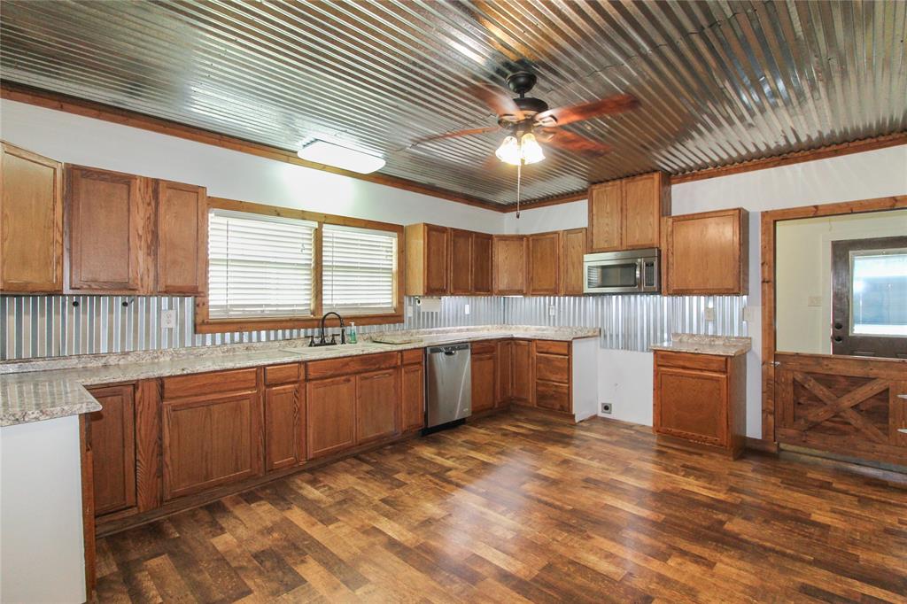455 Hughes Cemetery Road Italy, TX 76651 - Photo 28 of 40 a kitchen with stainless steel appliances kitchen island granite countertop a sink cabinets and wooden floor