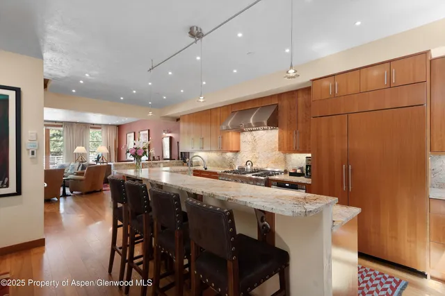 a kitchen with stainless steel appliances granite countertop a table chairs sink and stove top oven