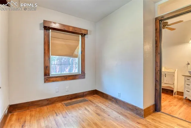 a view of empty room with wooden floor and a window