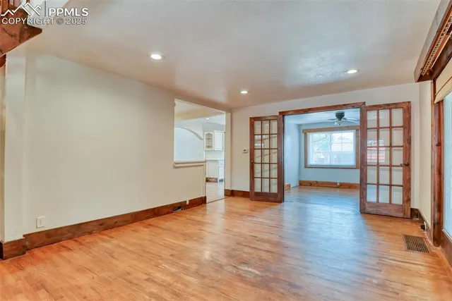 an empty room with wooden floor and windows