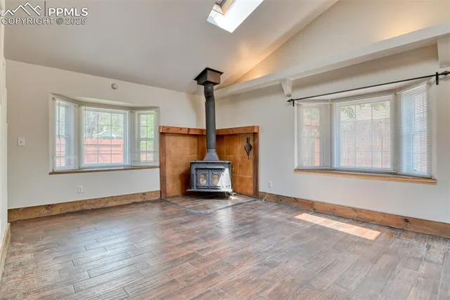 a view of an empty room with wooden floor and a fireplace