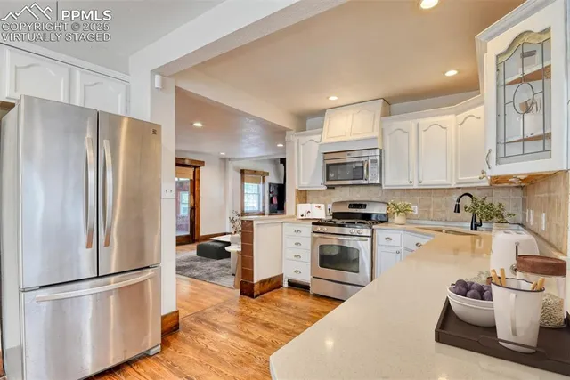 a kitchen with a refrigerator a stove top oven and white cabinets