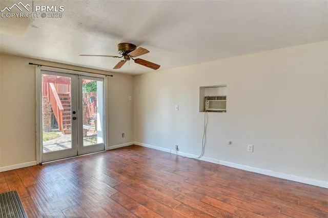 an empty room with wooden floor a ceiling fan and windows