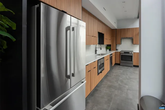 a kitchen with stainless steel appliances a refrigerator a stove a sink dishwasher and wooden cabinets