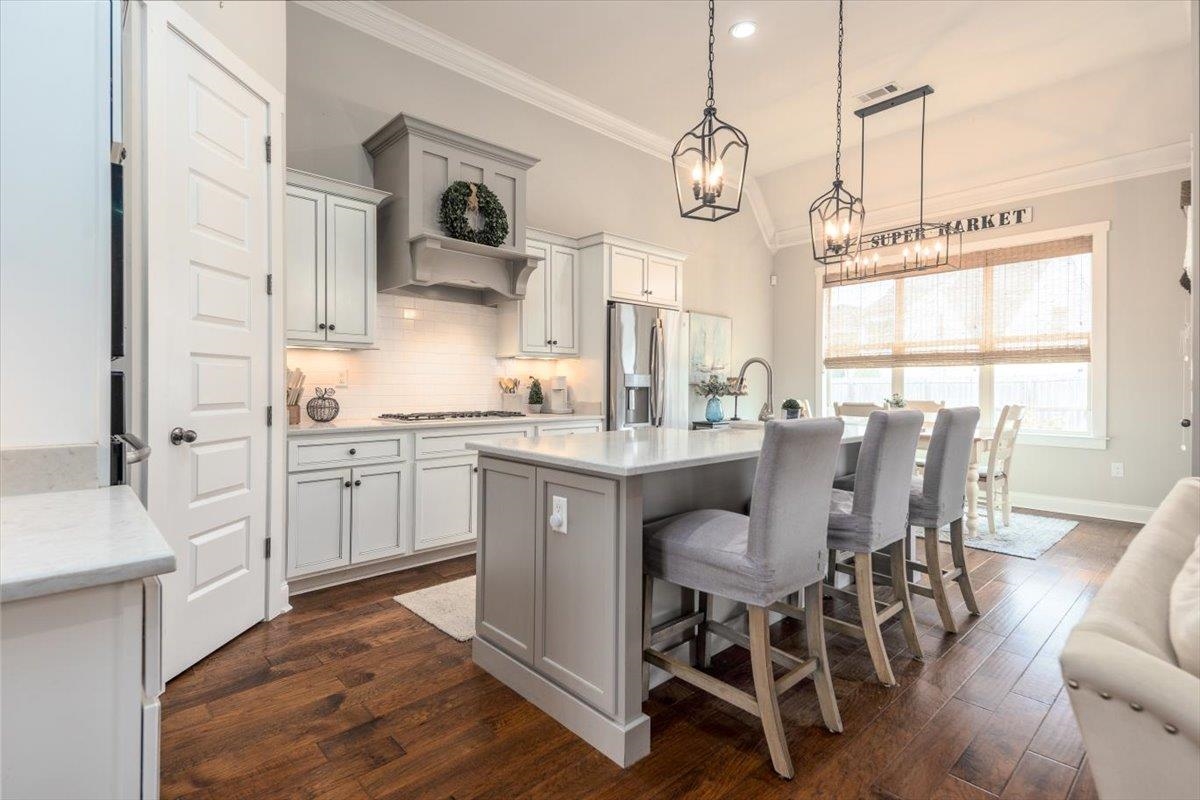 608 Cypress Run Cove Collierville, TN 38017 - Photo 12 of 40 Kitchen with a center island with sink, a kitchen bar, dark wood-style floors, vaulted ceiling, and crown molding