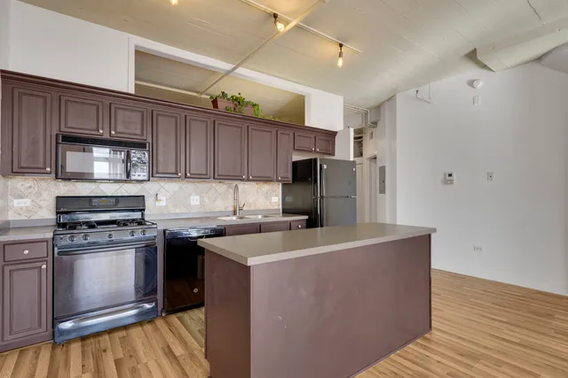 a kitchen with stainless steel appliances granite countertop a stove top oven a sink and a refrigerator