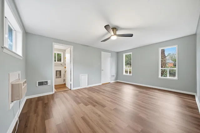 an empty room with wooden floor and windows