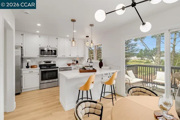a kitchen with stainless steel appliances granite countertop a stove a refrigerator a sink dishwasher a dining table and chairs with wooden floor