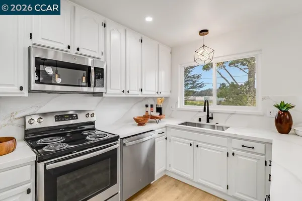 a kitchen with stainless steel appliances granite countertop a stove a sink cabinets and a dining table