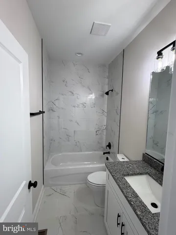 a bathroom with a granite countertop sink a toilet and shower