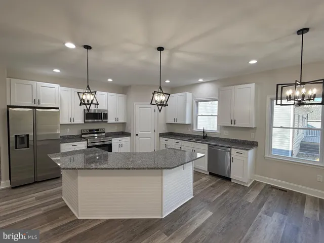 a kitchen with stainless steel appliances granite countertop a sink refrigerator and cabinets