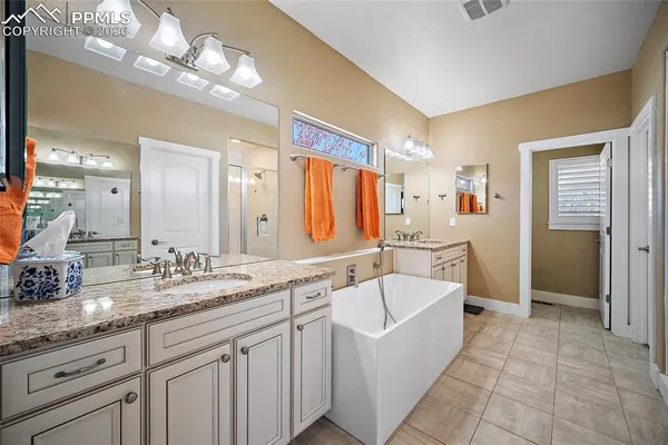 a spacious bathroom with a granite countertop double vanity sink a mirror and a bathtub