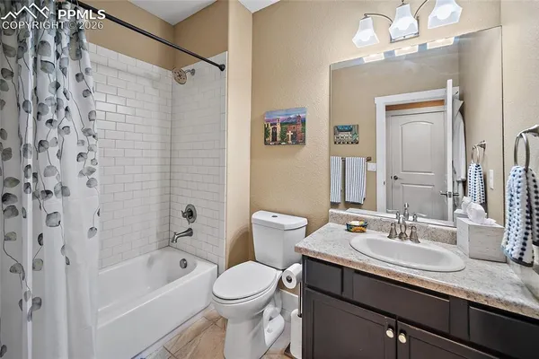 a bathroom with a granite countertop sink a toilet a mirror a bathtub and shower