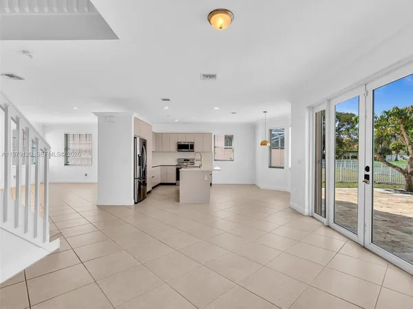 a view of kitchen with stainless steel appliances kitchen island granite countertop a refrigerator a stove a sink and white cabinets with wooden floor