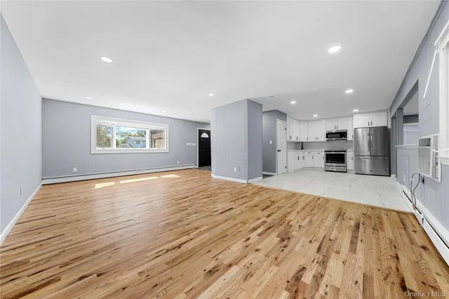 a view of empty room with wooden floor and a window