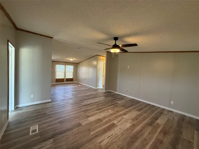 an empty room with wooden floor fan and windows