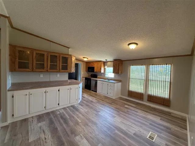 a large kitchen with stainless steel appliances granite countertop a large window a oven and white cabinets