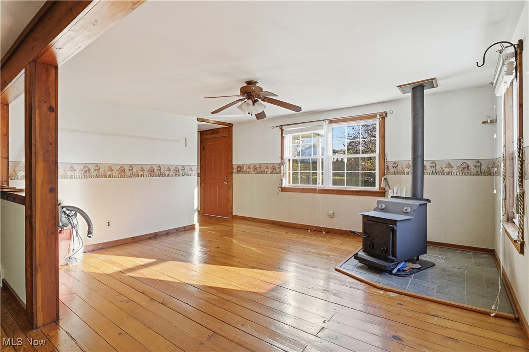 3275 Ranfield Road Kent, OH 44240 - Photo 15 of 33 Unfurnished living room featuring a wood stove, wood-type flooring, and a ceiling fan