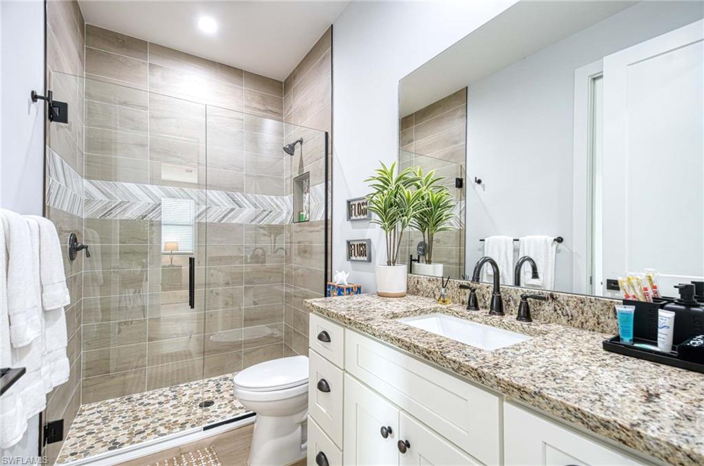 1147 Steeves Avenue Naples, FL 34104 - Photo 9 of 35 a bathroom with a granite countertop sink a toilet a mirror and shower