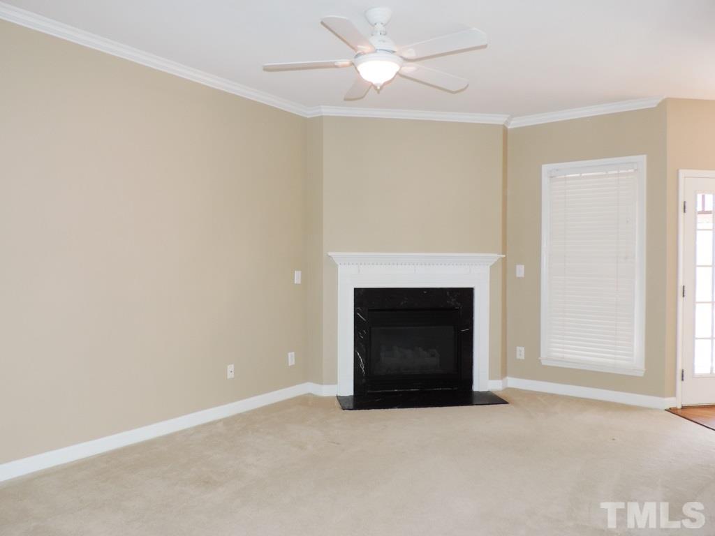 1901 Crag Burn Lane Raleigh, NC 27604 - Photo 6 of 16 an empty room with a fireplace and fan
