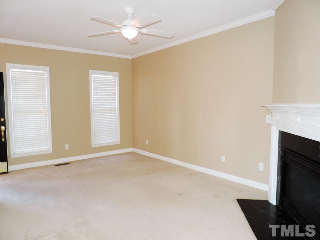 1901 Crag Burn Lane Raleigh, NC 27604 - Photo 7 of 16 an empty room with a fireplace and a ceiling fan