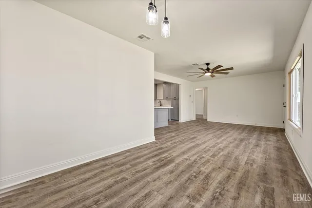 a view of a livingroom with a chandelier fan and wooden floor