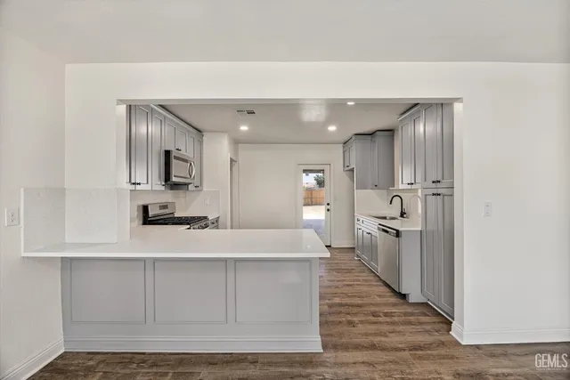 a large white kitchen with kitchen island a sink stainless steel appliances and cabinets