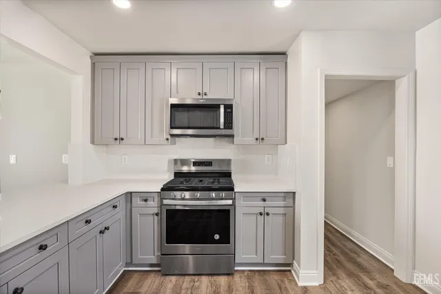 a kitchen with cabinets stainless steel appliances and wooden floor
