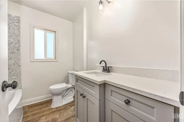 a bathroom with a granite countertop toilet sink and mirror