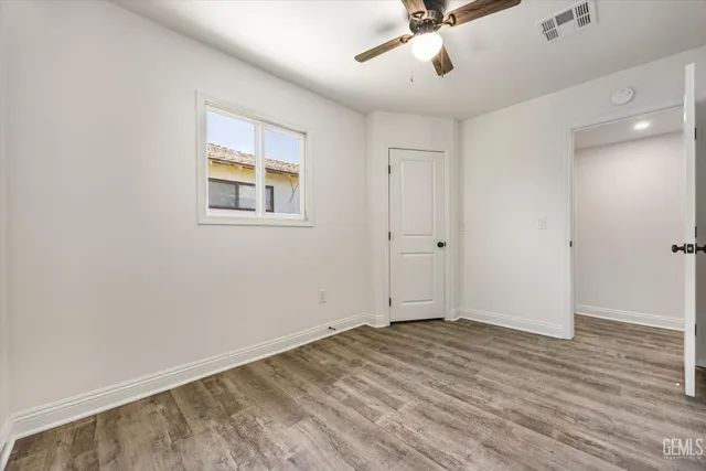 a view of empty room with wooden floor and fan