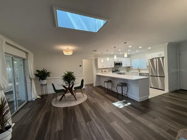 a living room with stainless steel appliances kitchen island granite countertop furniture wooden floor and a large window