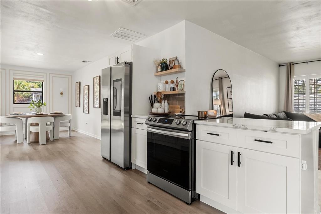 611 Bryan Court Altamonte Springs, FL 32701 - Photo 16 of 37 a kitchen with stainless steel appliances white cabinets and wooden floors