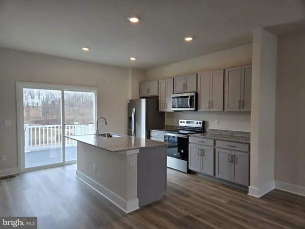 a kitchen with stainless steel appliances granite countertop a stove top oven a refrigerator a sink and dishwasher with wooden floor