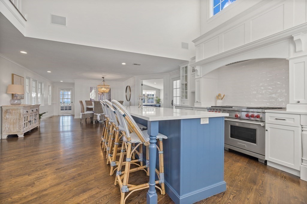 48 Collier Road Scituate, MA 02066 - Photo 14 of 42 a kitchen with stainless steel appliances granite countertop a stove top oven a sink a dining table and chairs with wooden floor
