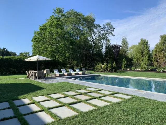 a view of a swimming pool with a table and chairs under an umbrella