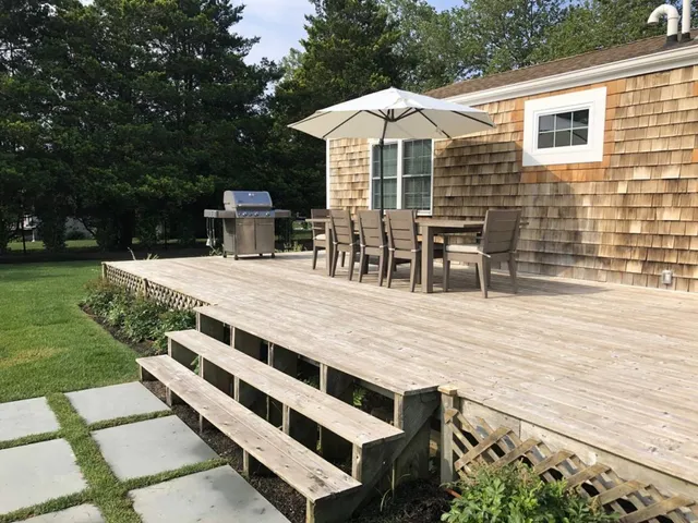 a view of a patio with a dining table and chairs with wooden floor and fence