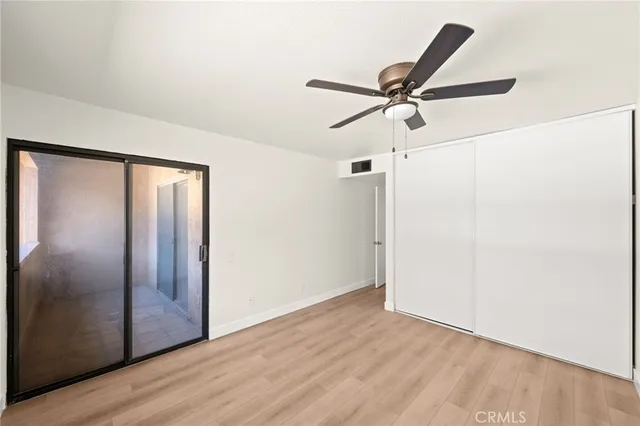 a view of a hallway with wooden floor and a ceiling fan