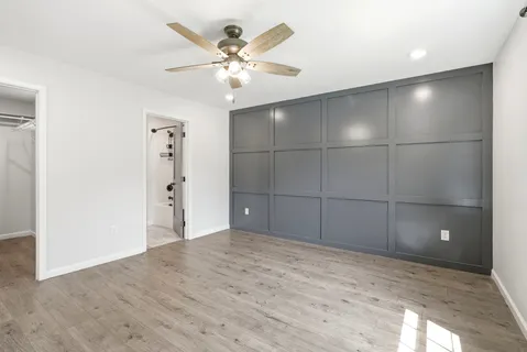 an empty room with wooden floor and a ceiling fan
