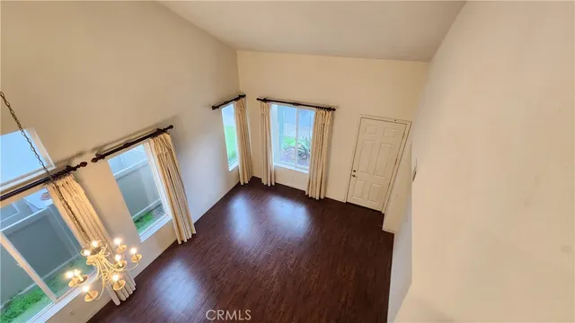 a view of an empty room with wooden floor and stairs