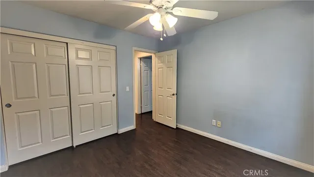 an empty room with wooden floor and ceiling fan