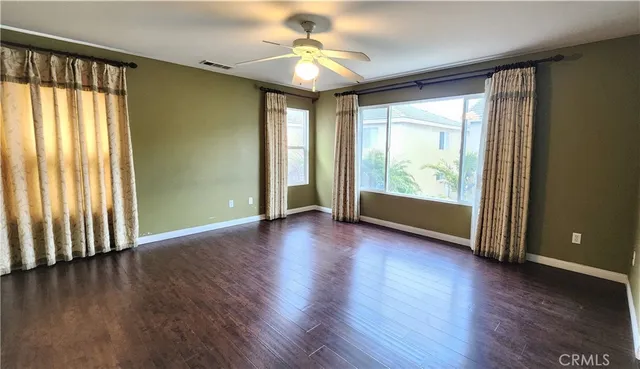 an empty room with wooden floor and windows with curtains view